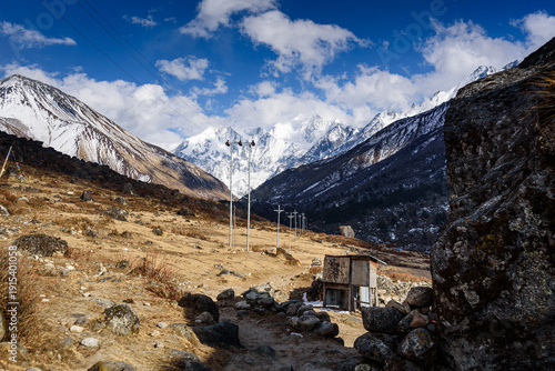 Small shelter and prayer flags along mountain path with stunning view of snow-covered Gangchempo, Langtang Himalay, Nepal