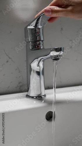 Close-Up of water flowing from modern chrome faucet in bathroom sink.