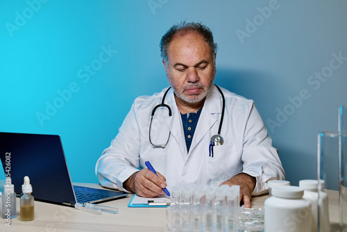 Middle aged family doctor working in modern office. Medicine service and wellness. Healthcare.