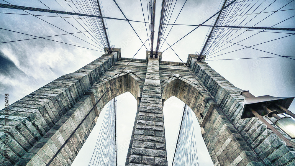 Obraz premium Brooklyn Bridge stone pillars captured from below highlighting structural details and grandeur