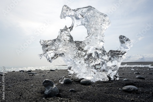 Ice, piece of ice with holes on the black sand beach, on the black lava beach Diamond Beach, southeast Iceland, Iceland