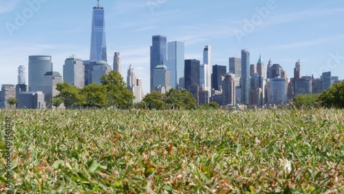 New York City Manhattan Downtown Financial District skyline, World Trade Center tower from New Jersey Liberty state park, United States. Green grass lawn and urban cityscape, skyscraper buildings.