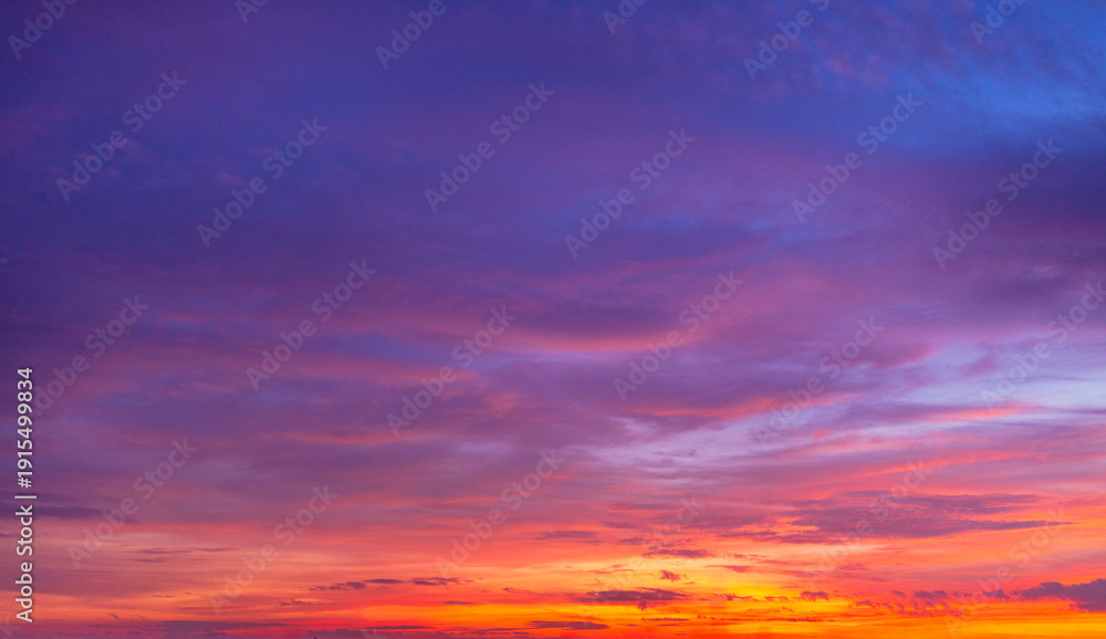 Fototapeta premium Dramatic sunset sky with vibrant orange and purple clouds at twilight,A breathtaking panoramic view of a colorful sunset sky featuring a mix of fiery orange, deep purple, and blue hues.
