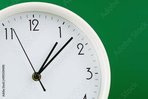 A clock telling the time against a green background, reflecting the concept of time and the value of time working with limited time and the constraints of precious time.