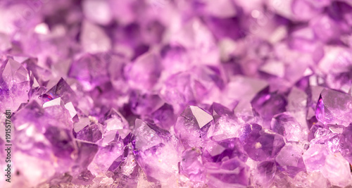 Amethyst purple crystals. Gems. Mineral crystals in the natural environment. Texture of precious and semiprecious stones. Seamless background with copy space colored shiny surface of precious stones.