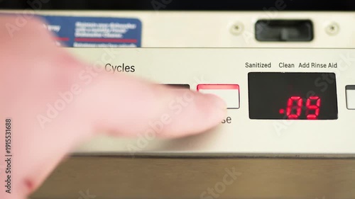 Person selecting rinse cycle on dishwasher control panel
