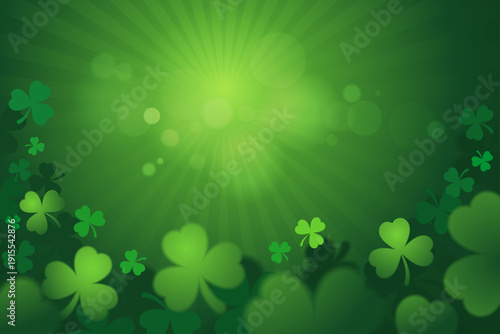 St. Patrick's Day background with green shamrocks and glowing light rays.