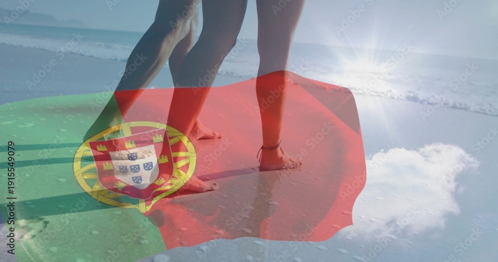 Fototapeta premium Standing couple showing legs, bare feet at beach edge, bikini, swim trunks, Portuguese flag overlay