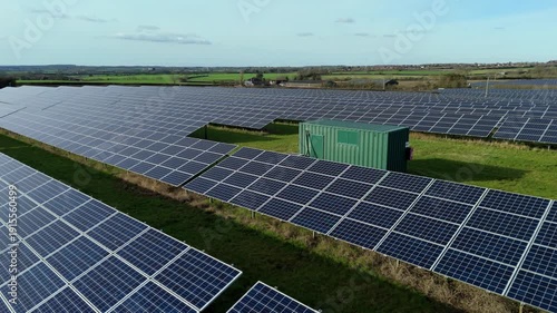 Close-up aerial drone view of a vast photovoltaic solar array integrated with a high-capacity battery energy storage system (BESS) site in the UK.