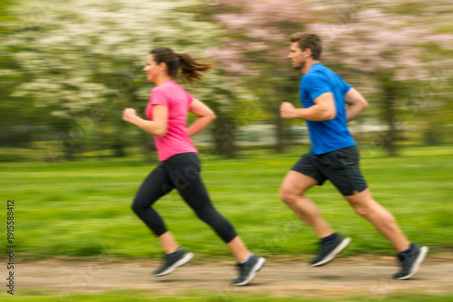 Young fitness couple in sportswear running together in park with action motion blur. Healthy lifestyle and training concept.
