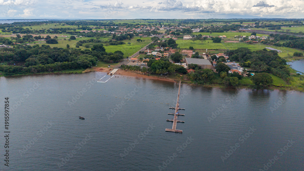 Obraz premium Aerial view of a serene lake with a small town and lush green landscape in the background
