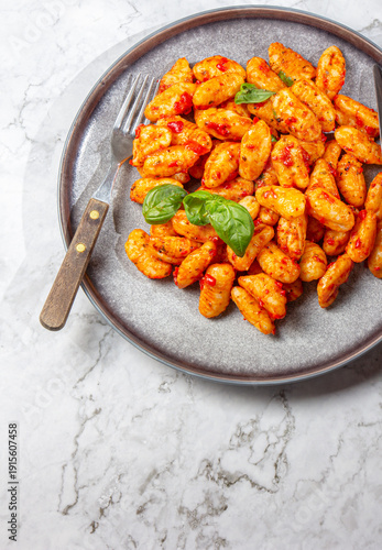Potato gnocchi with tomato sauce and basil on a gray plate 