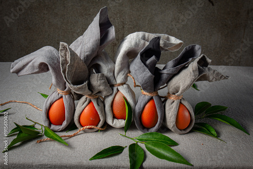 Easter table setting with decorated eggs wrapped as bunnies on a grey cloth background 