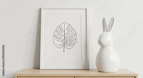 Minimalist framed leaf art beside a white bunny figurine on wooden shelf
