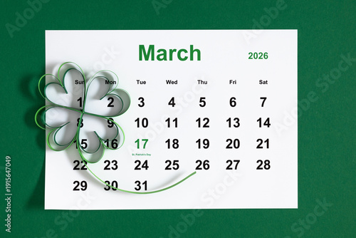 March 2026 calendar with paper handmade shamrock on green background. St. Patrick's Day date reminder, Irish holiday celebration concept, luck clover symbol, spring planning flat lay with copy space.