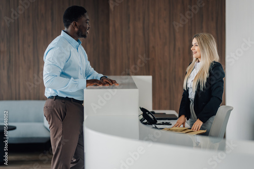 Tableau sur toile Client interacting with receptionist at modern office front desk