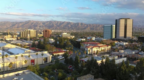 Aerial shot of the Burbank city with Verdugo Mountains at sunset. city's suburban layout and commercial buildings, with the rugged Verdugo Mountains rising in the background. 