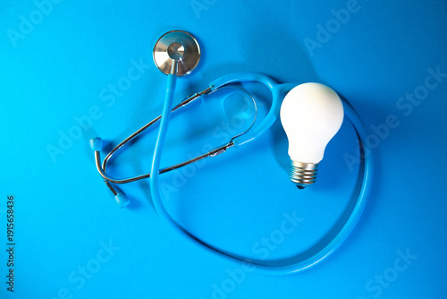 Stethoscope and light bulb on blue background. Concept of idea.