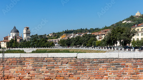 Brick wall foreground and Verona cityscape with church and river