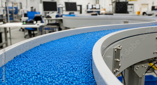 Blue polymer pellets on a factory conveyor belt