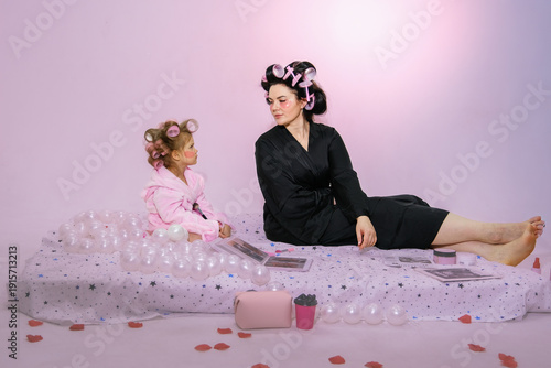 Moscow, Russia, 08.02.2026 Woman with hair rollers and little girl in robe makeup. Mother Daughter family concept, spa day at home. Self care for Mother Day.