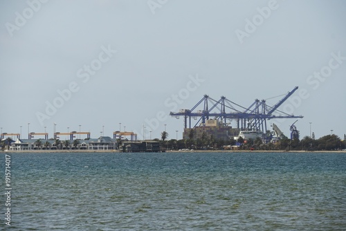 Tableau sur toile Industrial port of Swakopmund, Namibia, featuring large blue container cranes, stacked shipping containers, and a cargo vessel at the Atlantic Ocean waterfront