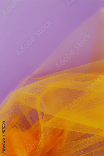 Bright orange tulle fabric on purple background.  Abstract transparent material curve wave.