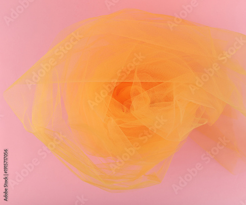 Bright orange tulle fabric on pink background.  Abstract transparent material curve wave.