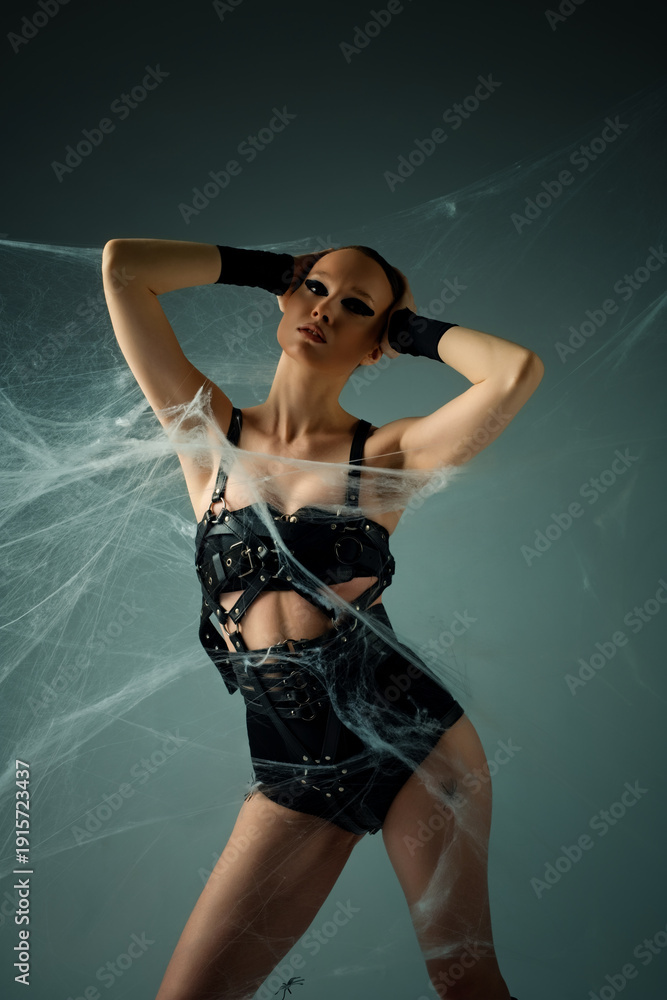 Obraz premium Woman in black leather harness and spiderwebs posing in a dark fantasy concept