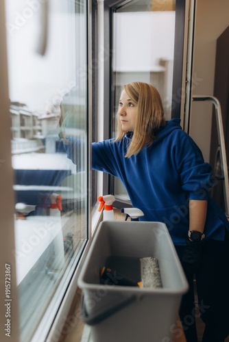 Woman cleaning window glass at residential building