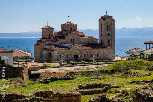 Bilde på lerret The reconstructed Church of Saints Clement of Ohrid and Panteleimon at Plaonik stands on a hillside above the sparkling blue Lake Ohrid, its domes and bell tower illuminated by bright sunshine