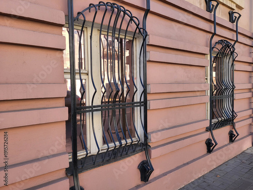 Pink facade with windows and wrought-iron grates.
