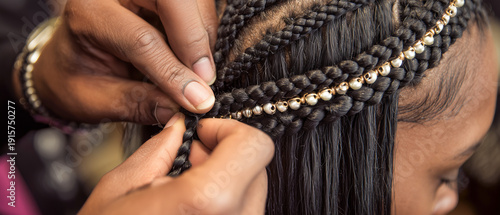 Close Up of African Female Hairstylist Braiding Hair with Golden Beads in Beauty Salon