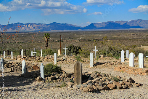 The back side of wooden grave markers in the famous, historic Boothill Graveyard in Tombstone, Arizona, USA against a mountain desert background with a blue cloudy sky.  The cemetery contains the grav