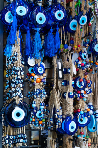 Schilderij op canvas Rows of blue glass nazar amulets hanging in bustling bazaar stall, mixed beads a
