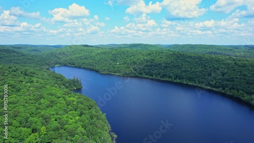 Aerial shot of BlueSky lake at crown land of Kents Mill Road and Pevensey road, near Pickerel Lake, Ontario, Canada. Epic wild lake and forest with trees. Travel and adventure during summer.