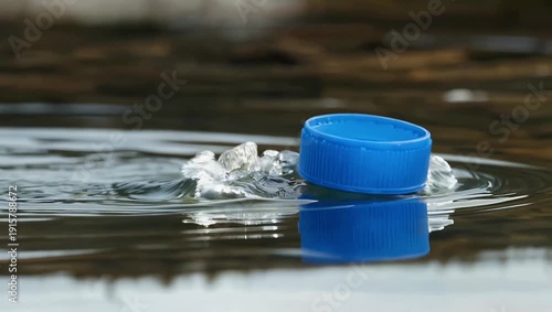 High resolution 4K slow motion pan of plastic blue bottle cap floating moving with water current emphasizing motion reflections playful dynamics beverage product stock 