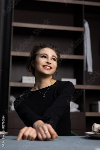 Smiling woman sitting at a table in a modern indoor setting during the day