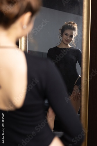 Dancer looks at herself in a mirror while preparing for a performance in a studio setting
