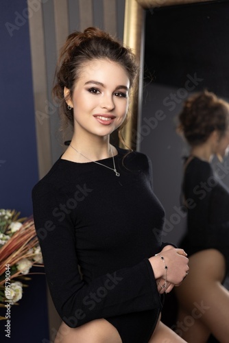 Portrait of a young woman smiling in a studio with a mirror and flowers