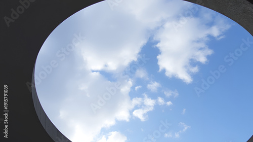 Cielo azzurro e nuvole che si intravedono dietro un cerchio di cemento. Speranza. Spazio per messaggio.
