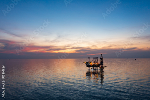 Aerial view of offshore jack up rig in a shipyard during sunset for oil and gas exploration and production.