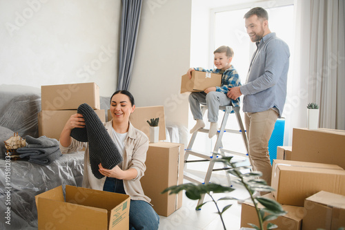 Foto Happy family moving to new home unpacking cardboard boxes