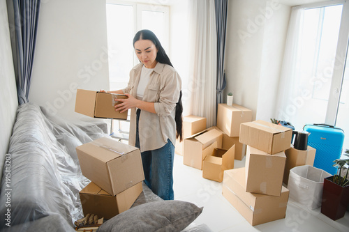 Photos Woman unpacking boxes in new apartment for relocation