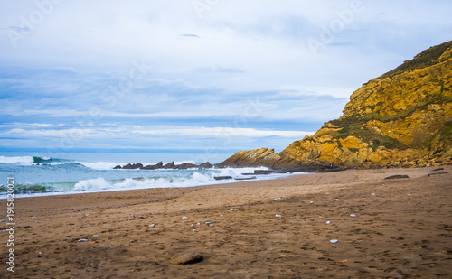 Rocky coastline and sandy beach with cliffs and ocean waves. High quality photo