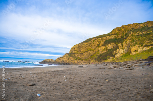 Rocky coastline and sandy beach with cliffs and ocean waves. High quality photo