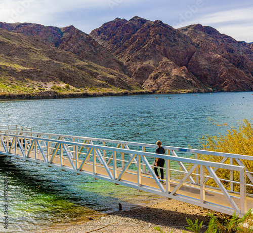 Female Tourist Walking on Fishing Pier on The Colorado River at Willow Beach Marina, Lake Mead National Recreation Area, Arizona, USA