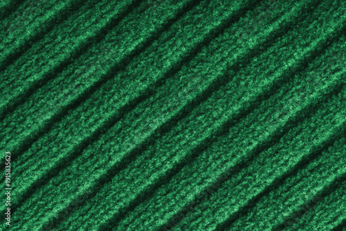 Close up, macro of green colored knitted fabric with diagonal relief ribbed pattern and soft wool texture. Detailed textile surface, knitwear background, fashion, backdrop, design element.