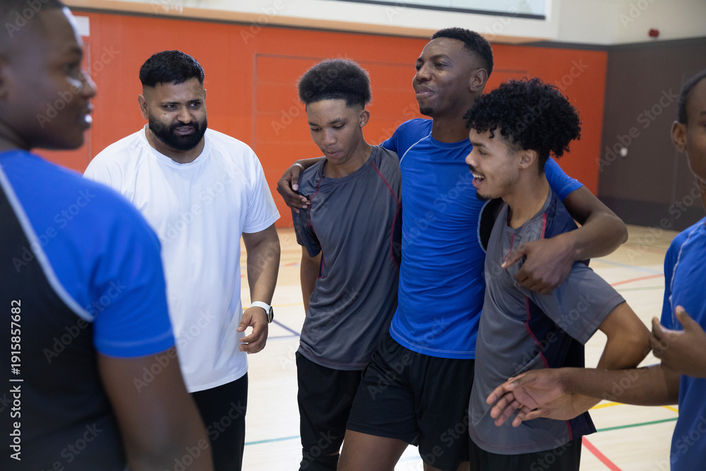 Obraz premium African American teenage male athletes huddling in sportswear on court lines, coach wearing watch