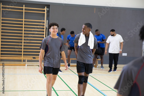 Φωτογραφία Teenage male athletes walking and talking in school gym in sportswear, wearing t
